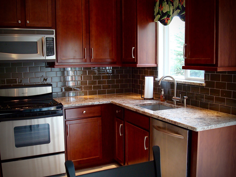 Photo: Kitchen featuring rich cherry cabinetry with modern handles and knobs.